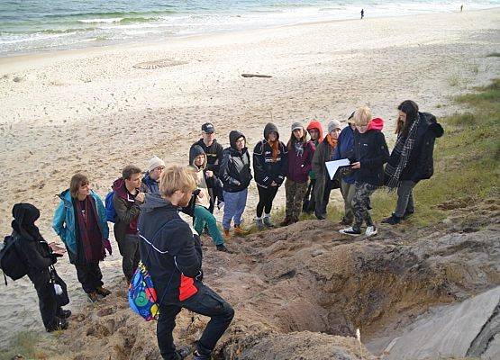 Studenci przy klifie w trakcie analizy odkrywki geologicznej