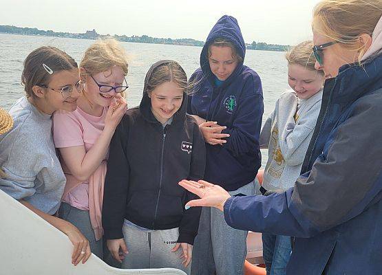 Pani oceanograf prezentuje dzieciom krabika na swojej dłoni.