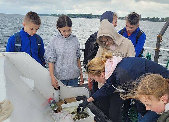 Kolejnarupa uczniów na kutrze w trakcie rejsu. Przegądanie próby połowowej