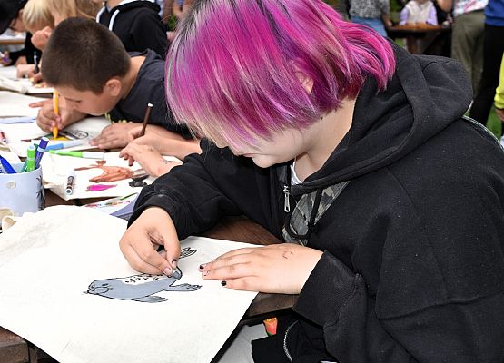 Na pierwszym planie dziewczyna rysuje fokę szarą na torbie płóciennej