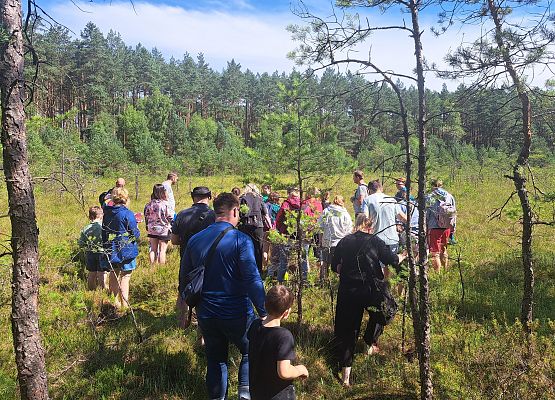 Grupa dorosłych i dzieci na torfowiska podczas wspólnej wycieczki w słoneczny dzień.