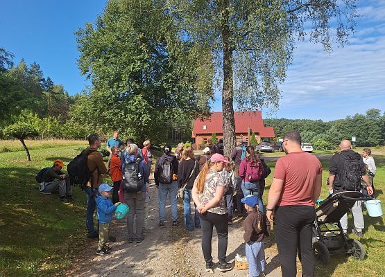 Grupa dzieci i dorosłych uczestniczy w aktywności na świeżym powietrzu.