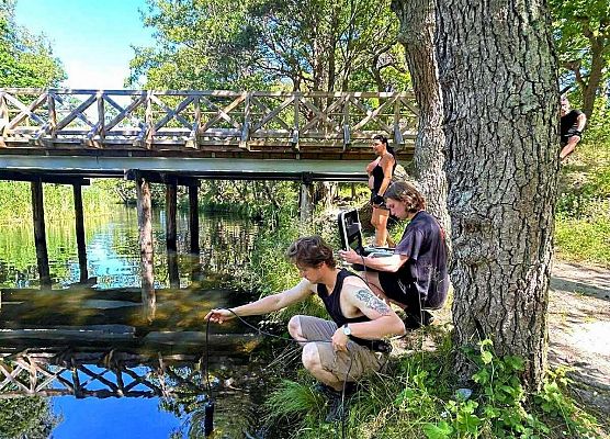 Grupa wykonkuje badania wody w rzece