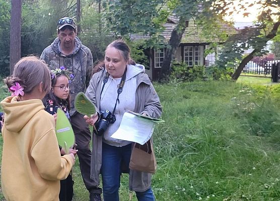 4 osoby, 2 trzymają symboliczny kwiat paproci