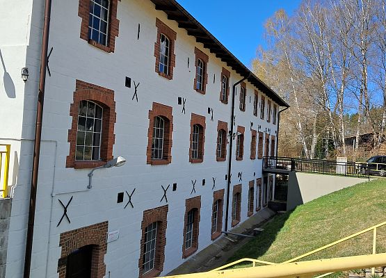 Widok z perspektywy rogu budynku. Biała elewacja  cegły wokół okien.