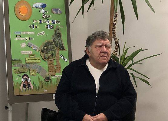 Mężczyzna z ciemnym ubraniu w tle kolorowy plakat.