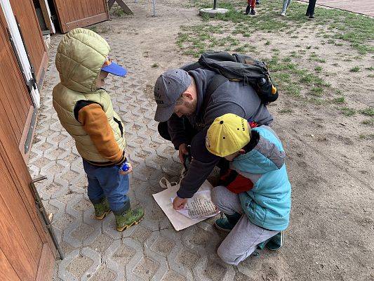 uczestnicy gry terenowej. Tata z dwójką dzieci czytają listę składników do zdobycia.