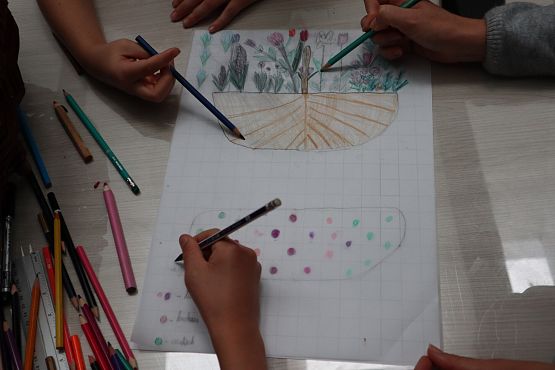 kadr na kilka dłoni, które rysują. Na rysunku kosz z kwiatami