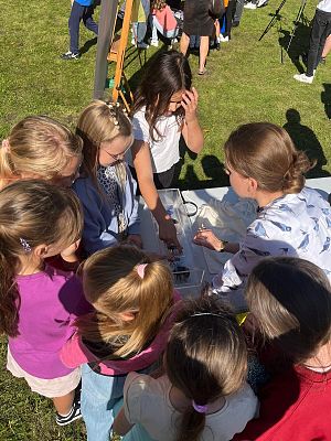 o owadach, fot. KK grupa dzieci wokół stołu na którym stoi gablotka z modelami owadów. zdjecie zrobione na podwórku.